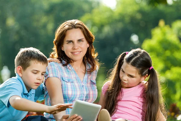 Lycklig familj använder laptop liggande på gräs — Stockfoto