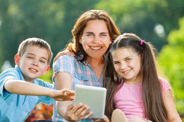 mutlu bir aile çim üzerinde yalan dizüstü kullanarak