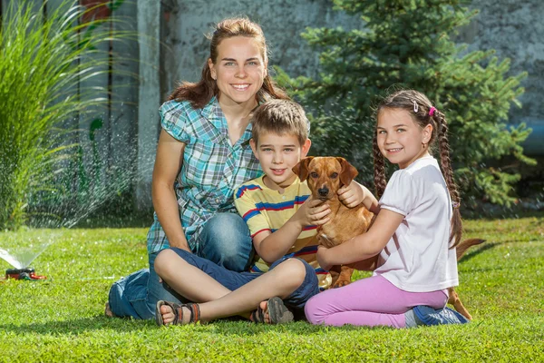 Una hermosa madre, hijo e hija de la familia con su perro mascota , — Foto de Stock