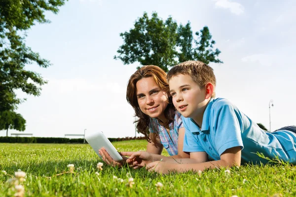 Famiglia felice utilizzando computer portatile sdraiato sull'erba — Foto Stock