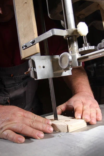 A craftsman cutting a plank of wood with bandsaw — Stock Photo, Image