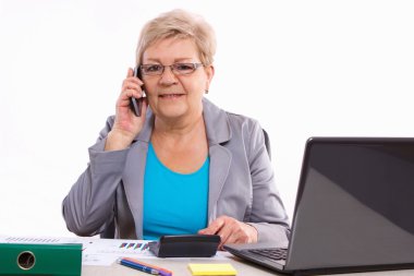 Yaşlı iş kadını cep telefonu konuşuyor ve ofiste masasında çalışan, iş kavramı