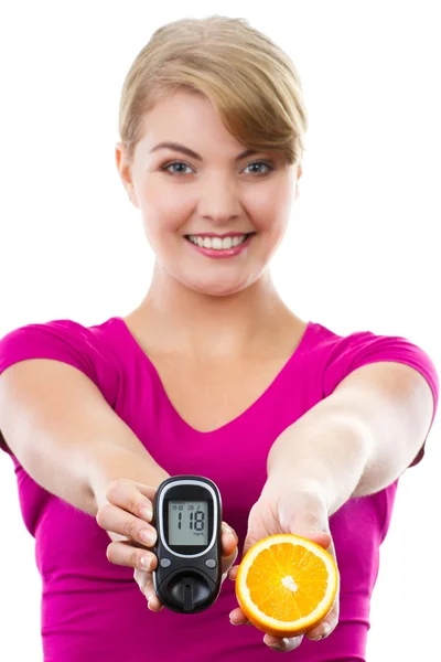 Mulher feliz segurando glicosímetro e laranja fresco, medindo e verificando o nível de açúcar, conceito de diabetes — Fotografia de Stock