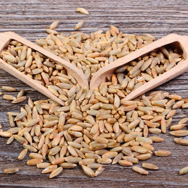 Rogge graan met lepel op houten achtergrond — Stockfoto