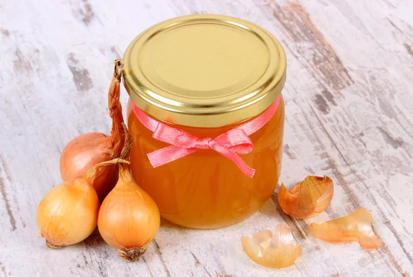 Miel orgánica fresca en frasco de vidrio y cebollas sobre fondo de madera, nutrición saludable y fortalecimiento de la inmunidad — Foto de Stock