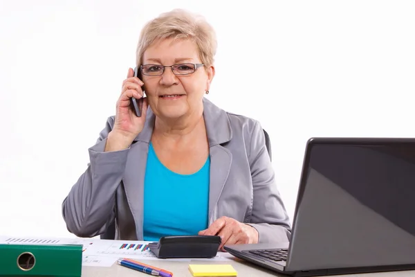 Oudere zakenvrouw praten op mobiele telefoon en werken bij haar Bureau in kantoor, Business concept — Stockfoto