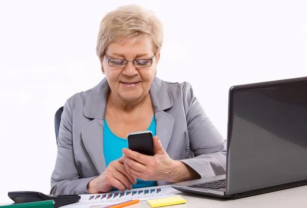 高齢者ビジネスの女性の携帯電話を使用して、オフィス、ビジネス コンセプトで彼女の机で働いて — ストック写真