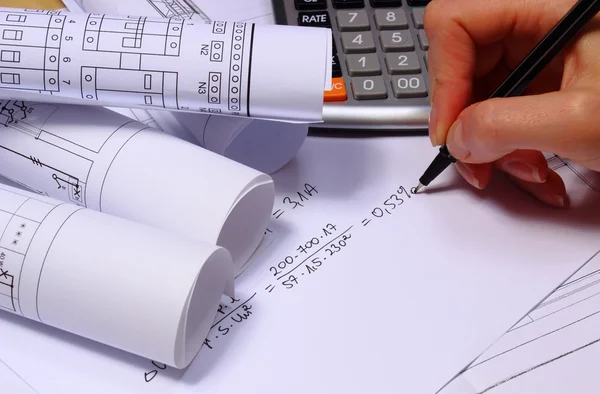 Rolls of electrical diagrams, calculator and mathematical calculations — Stock Photo, Image