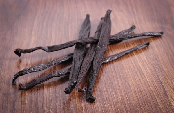 Fragrant vanilla sticks on wooden surface plank