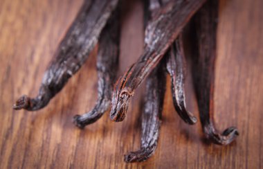 Fragrant vanilla sticks on wooden surface plank