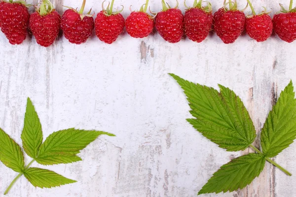 Fresh raspberries with leaf and copy space for text on old wooden background — 图库照片
