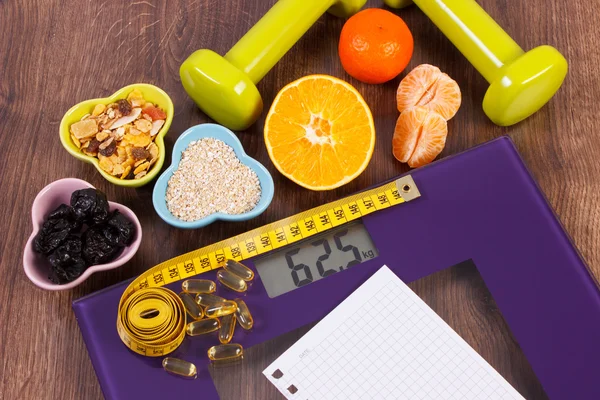 Digital scale with tape measure, tablets, dumbbells, fruits, muesli, slimming concept — Stock Photo, Image