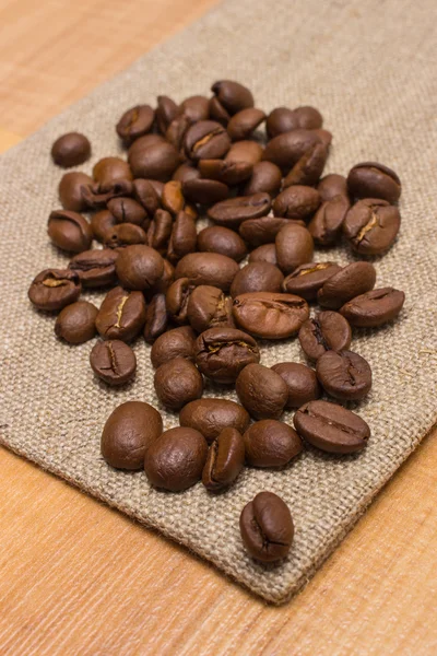 Altura de grãos de café em tela de juta na mesa — Fotografia de Stock