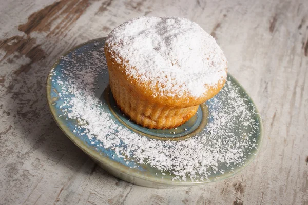 Свежие кексы с сахарной пудрой на деревянном фоне, вкусный десерт — стоковое фото