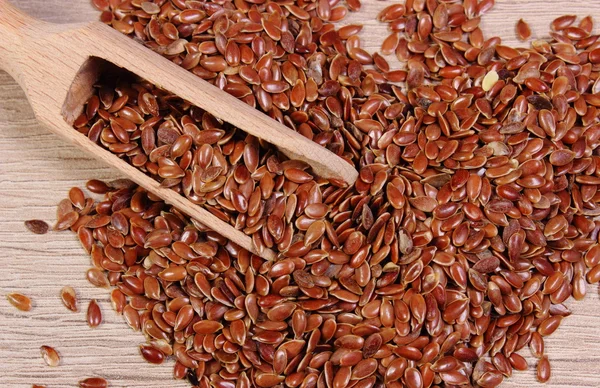 Heap of linseed with spoon on wooden background — Stock Photo, Image