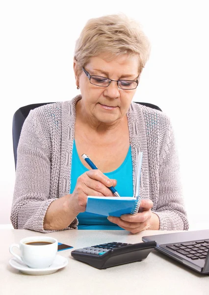 Femme âgée âgée écrivant dans un carnet ou un calendrier — Photo