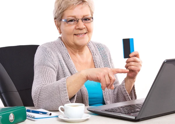 Oudere Senior vrouw het houden van creditcard en het tonen van laptop scherm, betalen via internet voor nutsbedrijf rekeningen of winkelen — Stockfoto