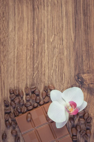 Vintage-Foto, Milchschokolade, Kaffeekörner und blühende Orchidee, Kopierplatz für Text — Stockfoto