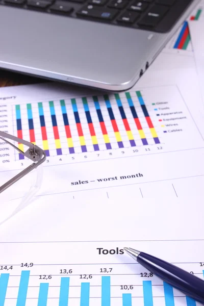 Pen, glasses and laptop on financial graph, business concept — Stockfoto