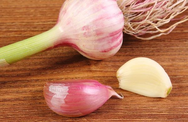 Whole garlic with roots and cloves on wooden table — Stock Photo, Image