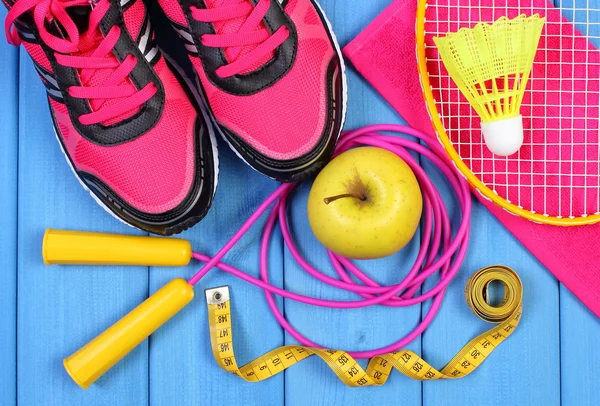 Par de zapatos deportivos de color rosa, manzana fresca y accesorios para el deporte en tablas azules — Foto de Stock