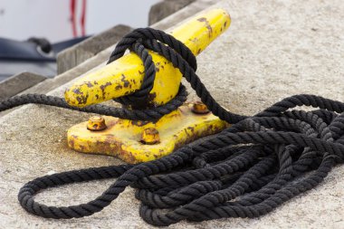 Yachting, black rope and yellow mooring bollard