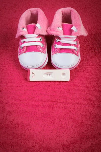Teste de gravidez com resultado positivo e sapatos de bebê em toalha macia, esperando por bebê, espaço de cópia para texto — Fotografia de Stock