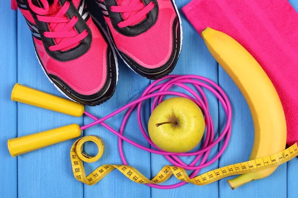 Par de zapatos deportivos de color rosa, frutas frescas y accesorios para fitness en tablas azules — Foto de Stock