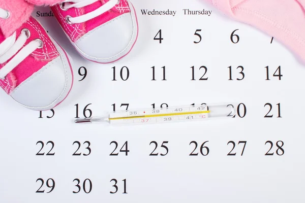 Termometro e abbigliamento per neonato in calendario, in attesa per il bambino — Foto Stock