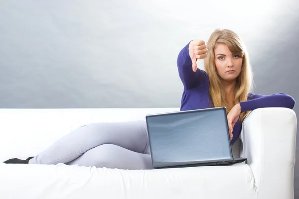 Mulher infeliz com laptop sentado no sofá e mostrando polegares para baixo, tecnologia moderna — Fotografia de Stock