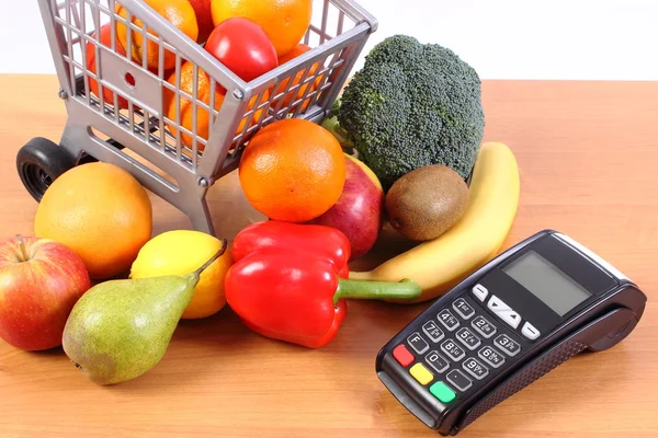 Payment terminal with fruits and vegetables, cashless paying for shopping, finance concept