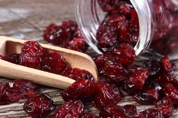 Cranberries spilling out of glass jar on wooden table — Stock Photo, Image