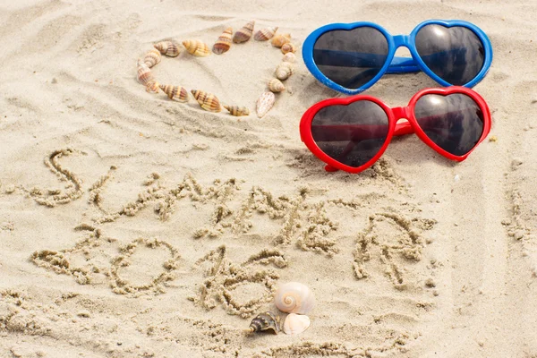 Été 2016 dessiné sur sable et coeur de coquillages avec lunettes de soleil — Photo