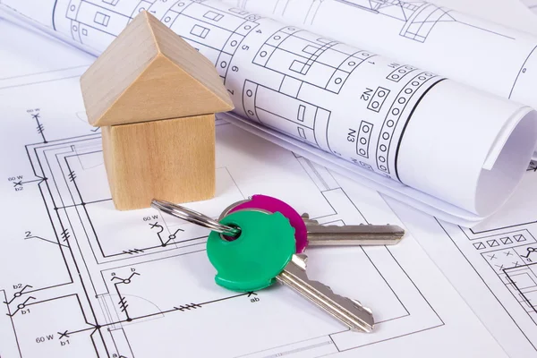 House of wooden blocks, rolls of diagrams and keys on construction drawing of house — Stock Photo, Image