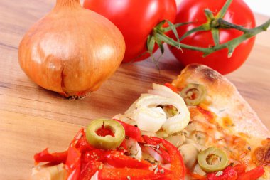 Dilim vejetaryen pizza, domates ve soğan ahşap yüzey üzerinde