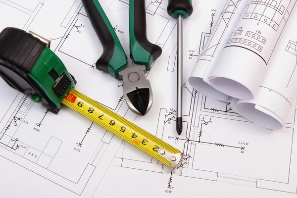 Work tools and rolls of diagrams on construction drawing of house — Stock Photo, Image