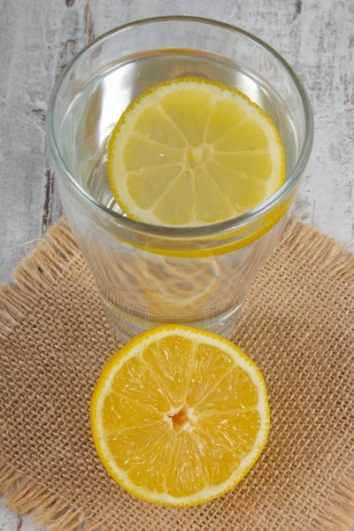 Свежий лимон и стакан чистой воды с ломтиком лимона, холодным лимонадом — стоковое фото