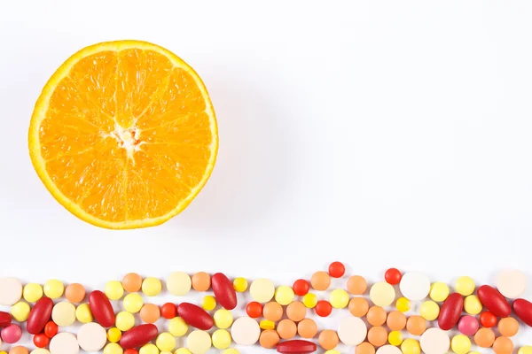 Colorful medical pills and fresh orange on white background, health care and healthy lifestyle concept, copy space for text — Stock Photo, Image