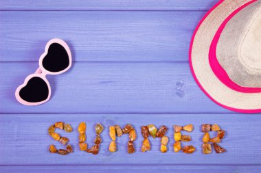 Word summer made of amber stones, sunglasses and straw hat on boards, summer time, copy space for text