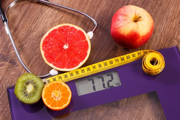 Elektronische weegschaal, centimeter en vers fruit met stethoscoop, vermageringsdieet en gezonde levensstijl — Stockfoto
