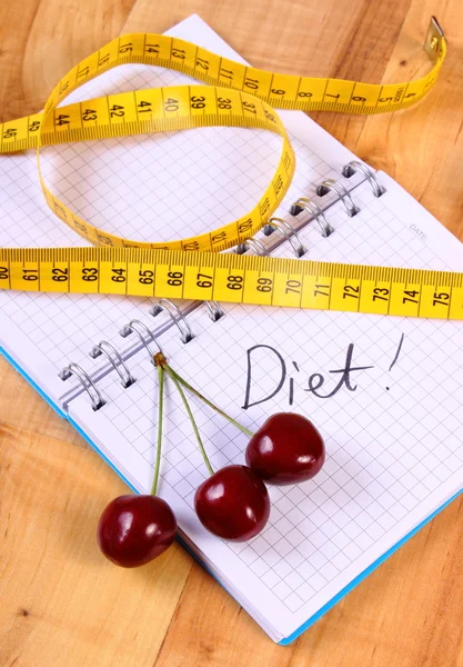 Cherry and centimeter with notebook, slimming and healthy food — Stockfoto