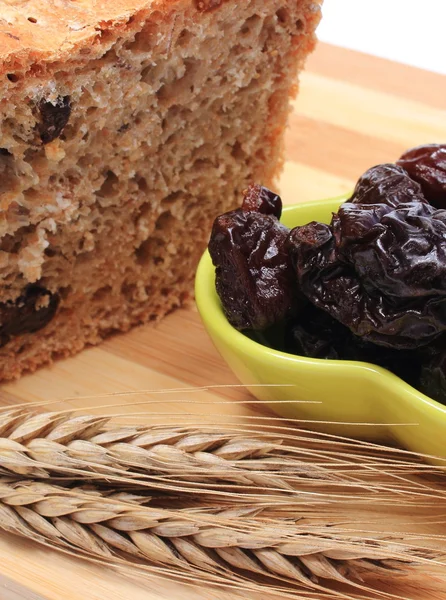 Gebakken volkoren brood, gedroogde pruimen en oren van tarwe — Stockfoto