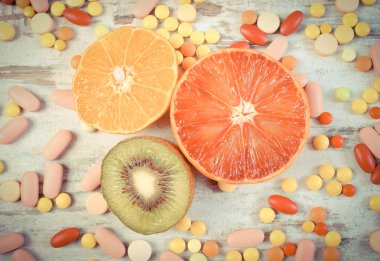 Vintage fotoğraf, Taze meyve ve renkli tıbbi haplar, sağlıklı beslenme ve tıbbi takviyeleri arasında seçim