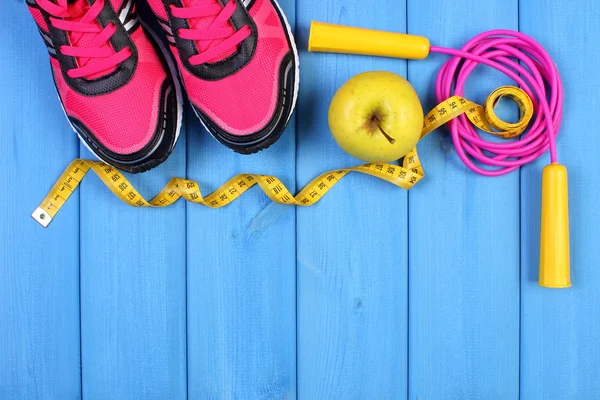 Par de zapatillas deportivas, manzana fresca y accesorios para fitness en tableros azules, espacio de copia para texto — Foto de Stock