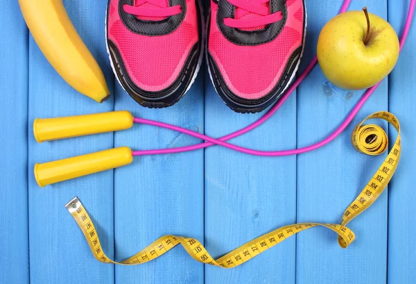 Par de zapatillas deportivas, frutas frescas y accesorios para fitness en tableros azules, espacio de copia para texto — Foto de Stock
