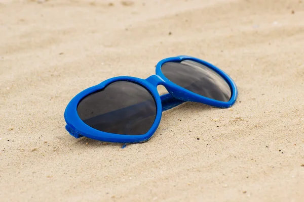 形心在沙滩上的蓝色太阳镜 — 图库照片