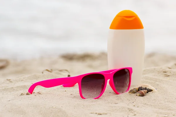 Concepto estacional, conchas, gafas de sol rosas y loción solar — Foto de Stock
