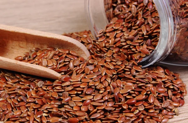 Linseed spilling out of jar on wooden background — Stock Photo, Image