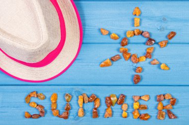 Word summer and shape of sun, straw hat on blue boards, summer time