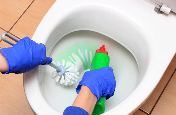 Mão de mulher em luva azul limpeza vaso sanitário — Fotografia de Stock